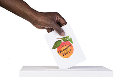 a voter's hand placing a ballot in a ballot box