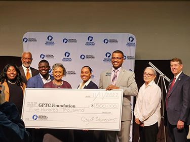 Mayor Jazzmin Cobble presents a check for $500,000 to the College's staff.